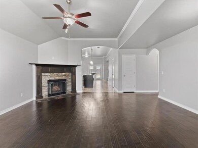 Unfurnished living room featuring a stone fireplace, arched walkways, a ceiling fan, wood-type flooring, and lofted ceiling