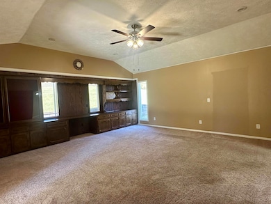 Unfurnished living room featuring lofted ceiling, plenty of natural light, light carpet, a textured ceiling, and a ceiling fan