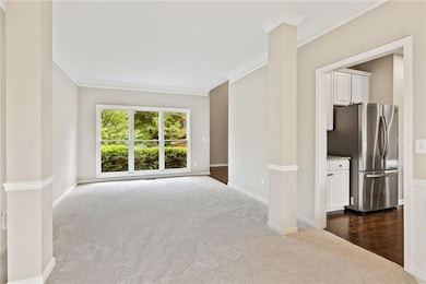 Spare room featuring dark carpet, crown molding, and baseboards