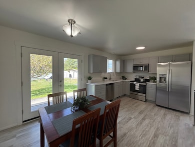 Kitchen with appliances with NEW stainless steel finishes, NEW cabinetry, light countertops, french doors, and light wood finished floors