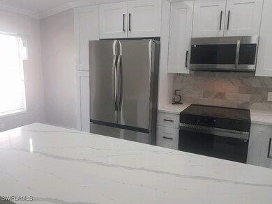 Kitchen featuring white cabinets, light stone coun