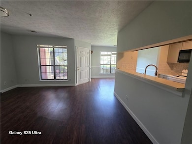 Unfurnished living room featuring dark wood-type flooring and a textured ceiling