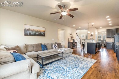 Living room with hardwood flooring and ceiling fan.