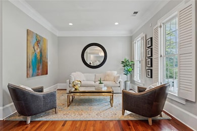 Living room featuring crown molding, healthy amount of natural light, wood finished floors, baseboards, and recessed lighting