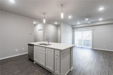 Kitchen with stainless steel dishwasher, hanging light fixtures, a kitchen island with sink, white cabinetry, and sink