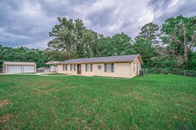 Ranch-style house with a garage, central AC, fence, a front lawn, and an outbuilding