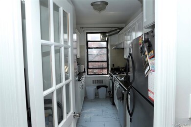 Kitchen with light marble finish floors, freestanding refrigerator, white cabinetry, white gas range oven, and range hood