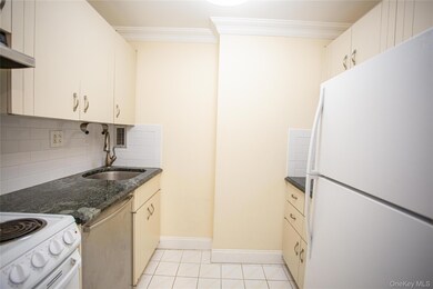 Kitchen with white appliances, tasteful backsplash, light tile patterned floors, dark stone counters, and ornamental molding