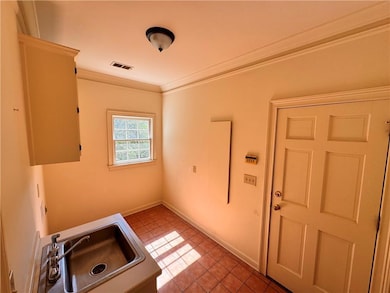 Laundry area with ornamental molding and light tile patterned floors