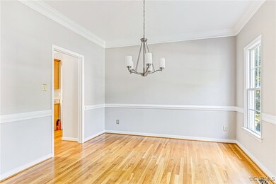 Empty room with a wealth of natural light, ornamental molding, a notable chandelier, and light wood-type flooring