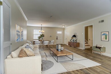 Living room with wood finished floors, visible vents, and ornamental molding virtually staged