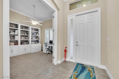 Foyer entrance with ornamental molding, ceiling fan, light tile patterned flooring, and light carpet
