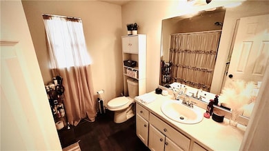 Full bath with curtained shower, toilet, and vanit