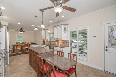 The kitchen island showcases a beautiful contrasting wood stain to compliment the cabinetry and a step down creates a permanent seating option for four people. Beyond the island, an expansive window with Plantation shutters looks toward the port-cochere.