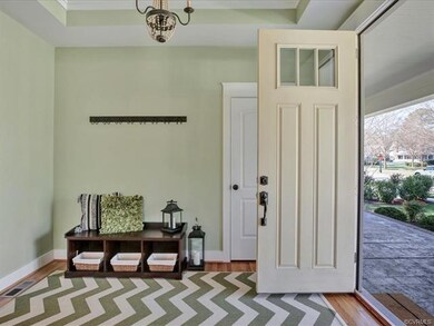 Foyer with tray ceiling, chandelier, and hardwood 