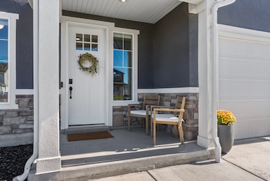 Property entrance featuring stone siding, a garage, covered porch, and stucco siding