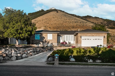 Ranch-style home with brick siding, a garage, a mountain view, and a fenced front yard