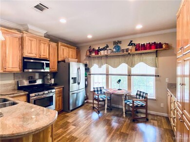 Kitchen featuring light stone countertops, backsplash, dark wood-type flooring, stainless steel appliances, and ornamental molding