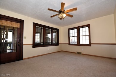 Carpeted empty room with a textured ceiling and a ceiling fan