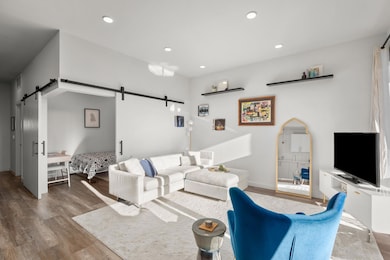 Living area with a barn door, wood finished floor