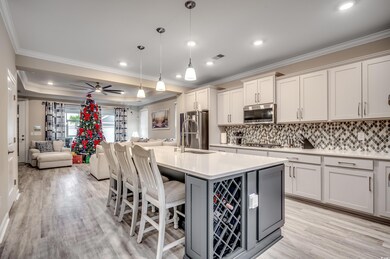 Kitchen featuring stainless steel appliances, crown molding, open floor plan, decorative backsplash, and light countertops