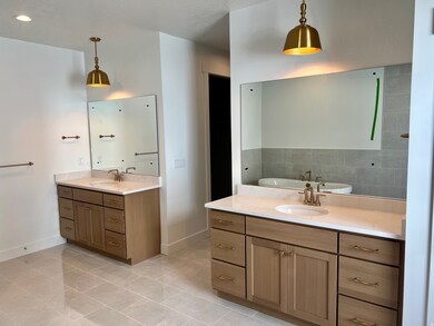 Full bathroom featuring light tile patterned floors, two vanities, and a tub to relax in