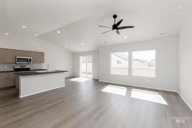 Kitchen with open floor plan, a kitchen island with sink, backsplash, stainless steel appliances, and a ceiling fan