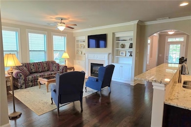 Living area, fireplace, arched walkway, ceiling fan, crown molding.
