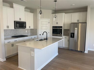 Kitchen featuring dark wood-style floors, appliances with stainless steel finishes, white cabinetry, and a sink