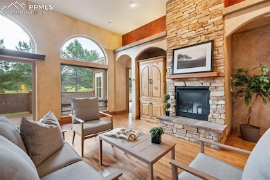 Living area with a high ceiling, hardwood floors, a fireplace, and arched walkways