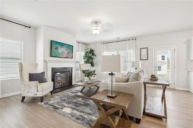 Living room featuring a glass covered fireplace, light wood-type flooring, and ceiling fan