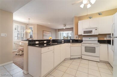 Kitchen featuring sink, white cabinets, white appliances, and kitchen peninsula
