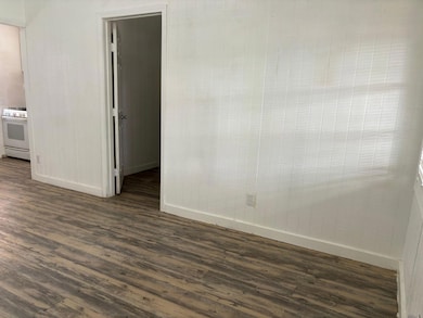 Empty room featuring baseboards and dark wood fin