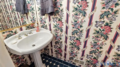 Bathroom with wallpapered walls and tile patterned floors