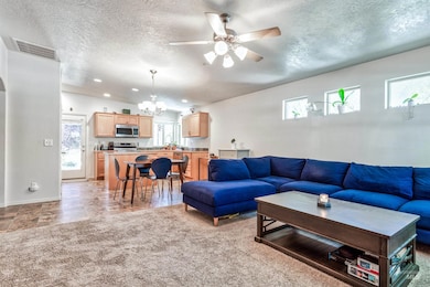 Living room featuring a chandelier, plenty of natural light, ceiling fan, a textured ceiling, and recessed lighting