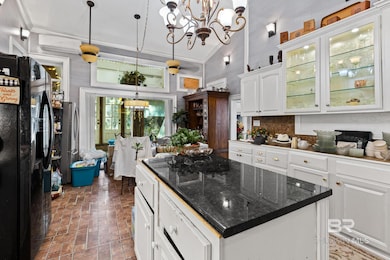 Kitchen with black refrigerator with ice dispenser, pendant lighting, white cabinets, glass insert cabinets, and high vaulted ceiling