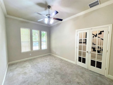 Empty room with crown molding, french doors, light colored carpet, and a ceiling fan