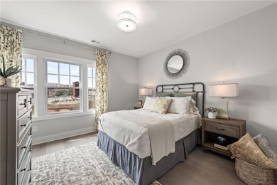 Bedroom with wood finished floors, visible vents, and multiple windows