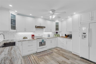 Kitchen featuring white appliances, white cabinetr