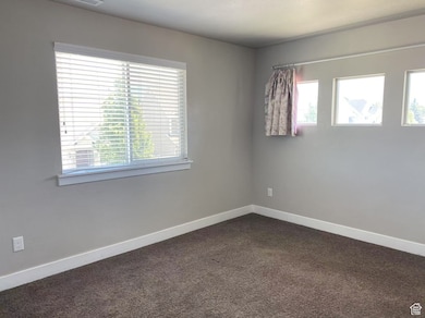 Unfurnished room with dark carpet and baseboards