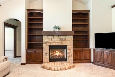 Unfurnished living room featuring light carpet, a fireplace, lofted ceiling, and arched walkways