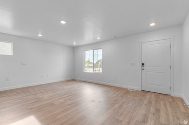 Empty room with light wood-style floors and recessed lighting