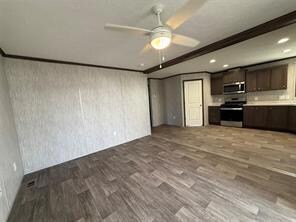 Kitchen with appliances with stainless steel finishes, dark brown cabinetry, light countertops, dark wood-style flooring, and a ceiling fan