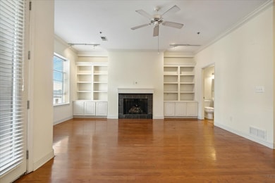 Unfurnished living room with rail lighting, ornamental molding, built in shelves, a fireplace, and a ceiling fan
