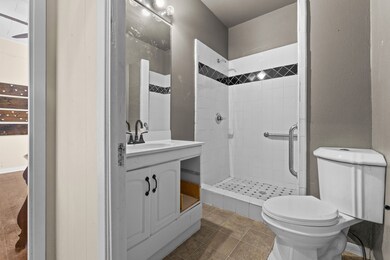 Full bath with vanity, a textured wall, tile patterned flooring, and a stall shower