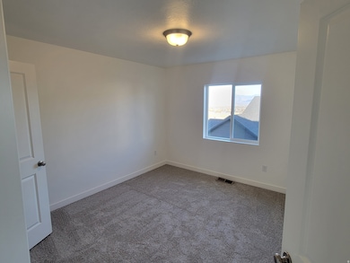 Carpeted spare room featuring baseboards