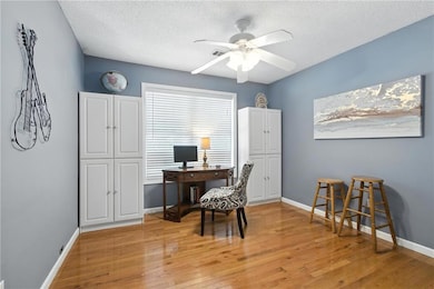 Office area featuring ceiling fan, light wood-style flooring, and a textured ceiling