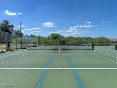 View of tennis court with fence and community bask