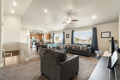 Carpeted living room featuring vaulted ceiling, a ceiling fan, wood finished floors, and recessed lighting