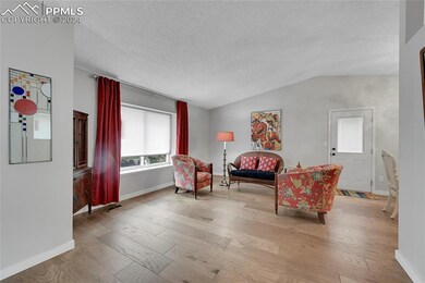 Sitting room featuring vaulted ceiling, a textured ceiling, and hardwood / wood-style flooring